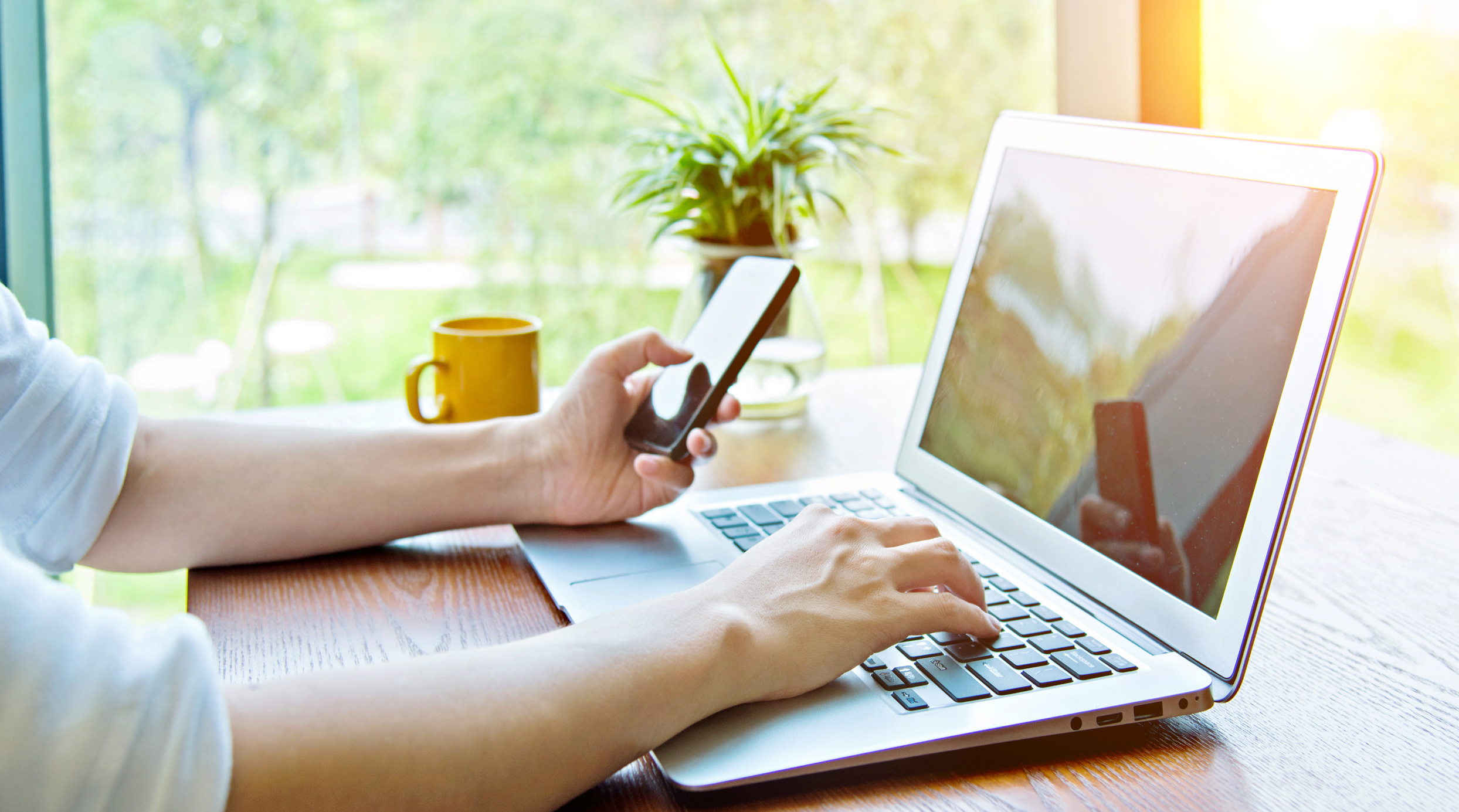 Woman using phone and laptop